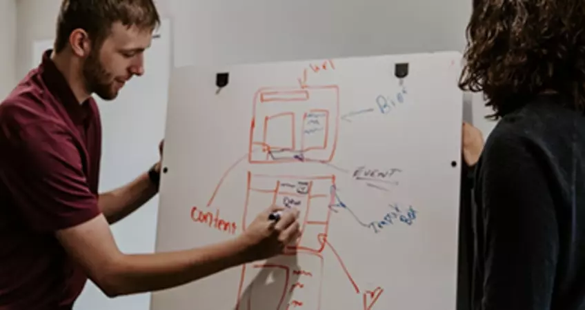 two people drawing on a board