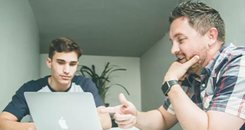 two man discussing while looking at a laptop